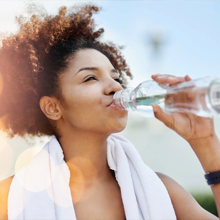 Person Drinking Water From A Plastic Bottle Outdoors